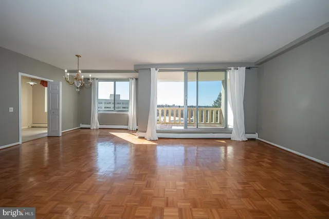 a view of an empty room with a window and wooden floor