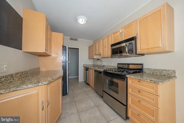 a kitchen with stainless steel appliances granite countertop a stove a sink and a microwave