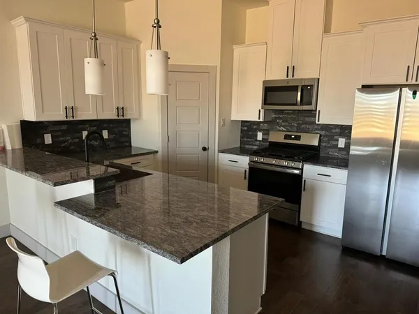 a kitchen with stainless steel appliances granite countertop a sink a stove and a refrigerator