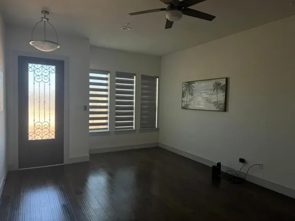 a view of an empty room with a window and wooden floor