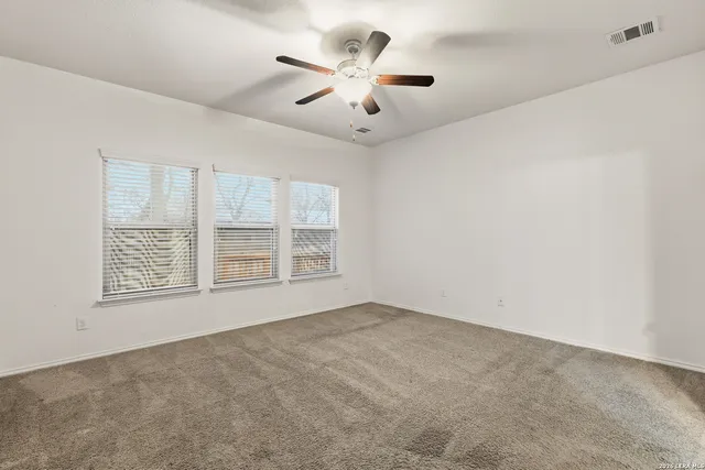 an empty room with windows and ceiling fan