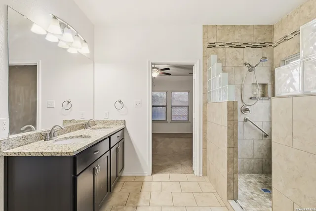 a bathroom with a granite countertop sink a mirror and shower