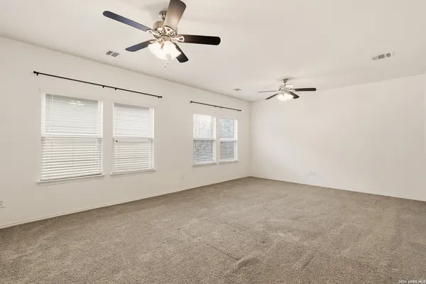 an empty room with windows and fan