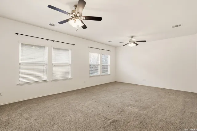 an empty room with windows and fan