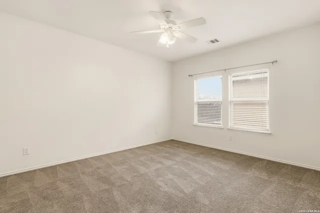 an empty room with a window and a fan