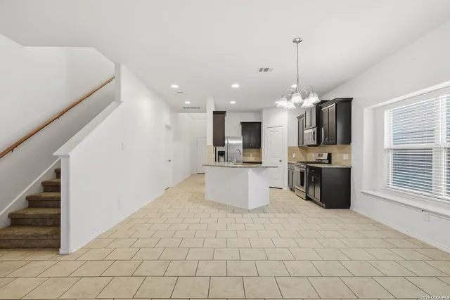 a large kitchen with stainless steel appliances kitchen island granite countertop a sink and a stove