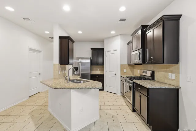 a kitchen with stainless steel appliances granite countertop a sink stove and cabinets