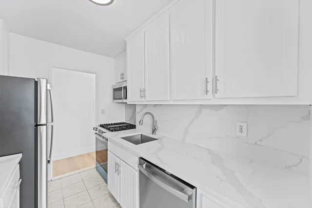 a kitchen with white cabinets and refrigerator