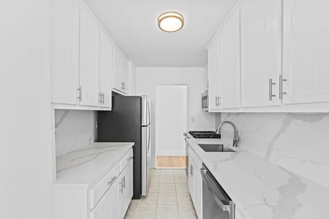 a kitchen with stainless steel appliances a sink a refrigerator and cabinets