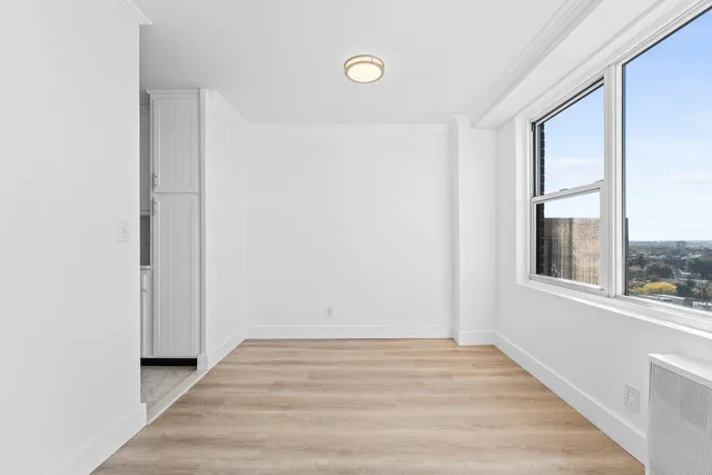 a view of an empty room with wooden floor and a window