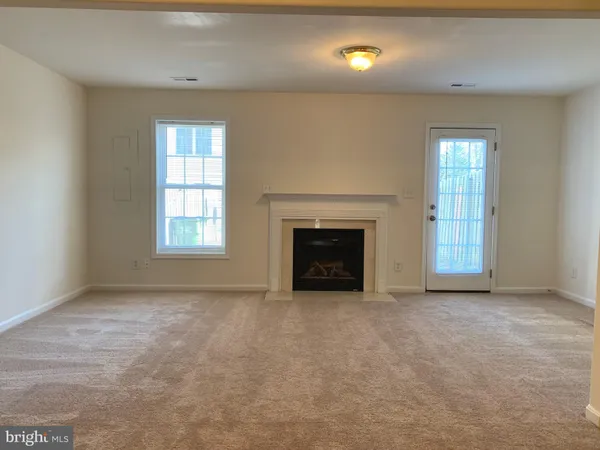 an empty room with windows and fireplace