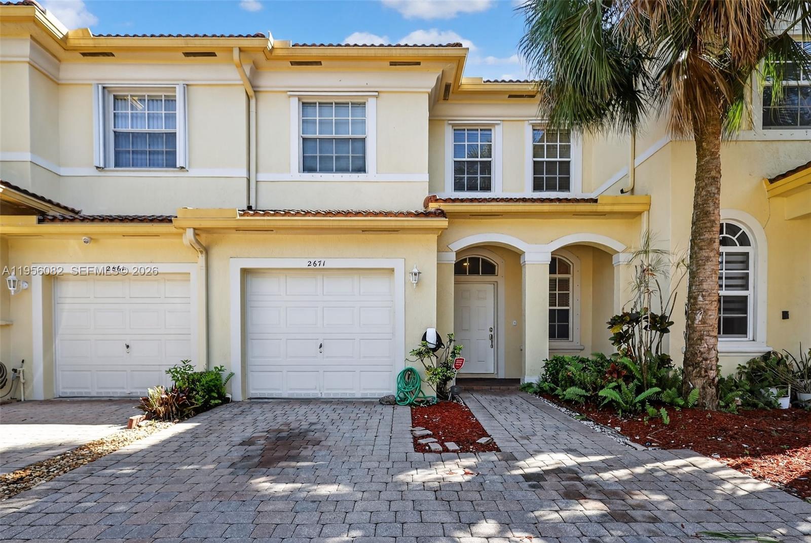 2671 Southwest 85th Terrace, Unit 103 Miramar, FL 33025 - Photo 47 of 49 a view of a white house with potted plants and a large tree