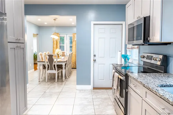 a kitchen with stainless steel appliances granite countertop a stove top oven a sink a dining table and chairs