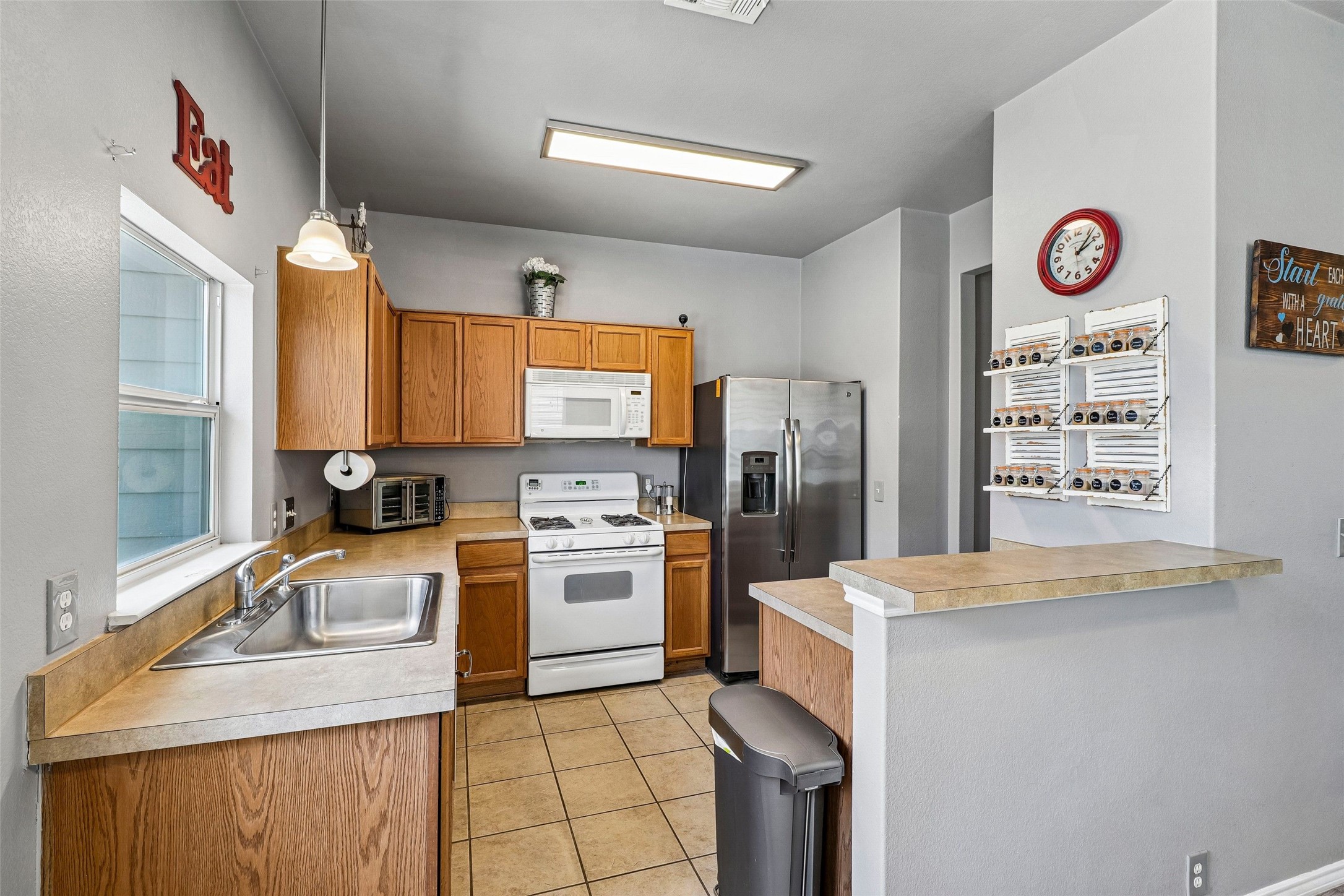311 A Utterback Kyle, TX 78640 - Photo 11 of 40 Kitchen featuring wood-finish cabinetry, tile flooring, stainless steel refrigerator, white range, and a breakfast bar with laminate countertops