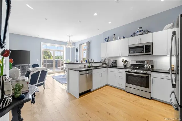 a kitchen with stainless steel appliances granite countertop a stove top oven a sink dishwasher a refrigerator and a dining table with wooden floor