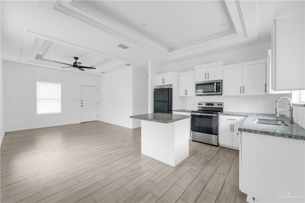 405 Rafael Drive San Juan, TX 78589 - Photo 11 of 13 a kitchen with granite countertop white cabinets a sink and wooden floor