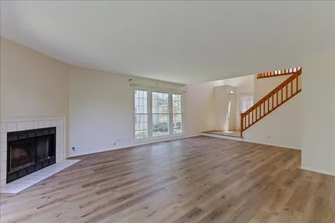 a view of an empty room with wooden floor fireplace and a window