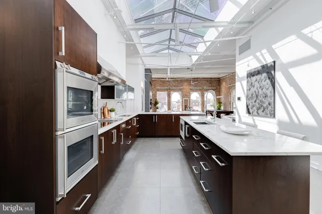 a large kitchen with a large counter top space a sink stainless steel appliances and a window