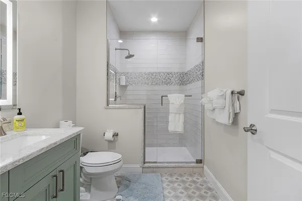a bathroom with a granite countertop sink a toilet and shower