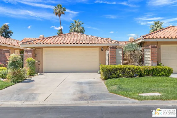 a front view of a house with a yard and potted plants
