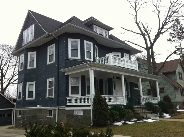 a view of a white house with large windows and a small yard