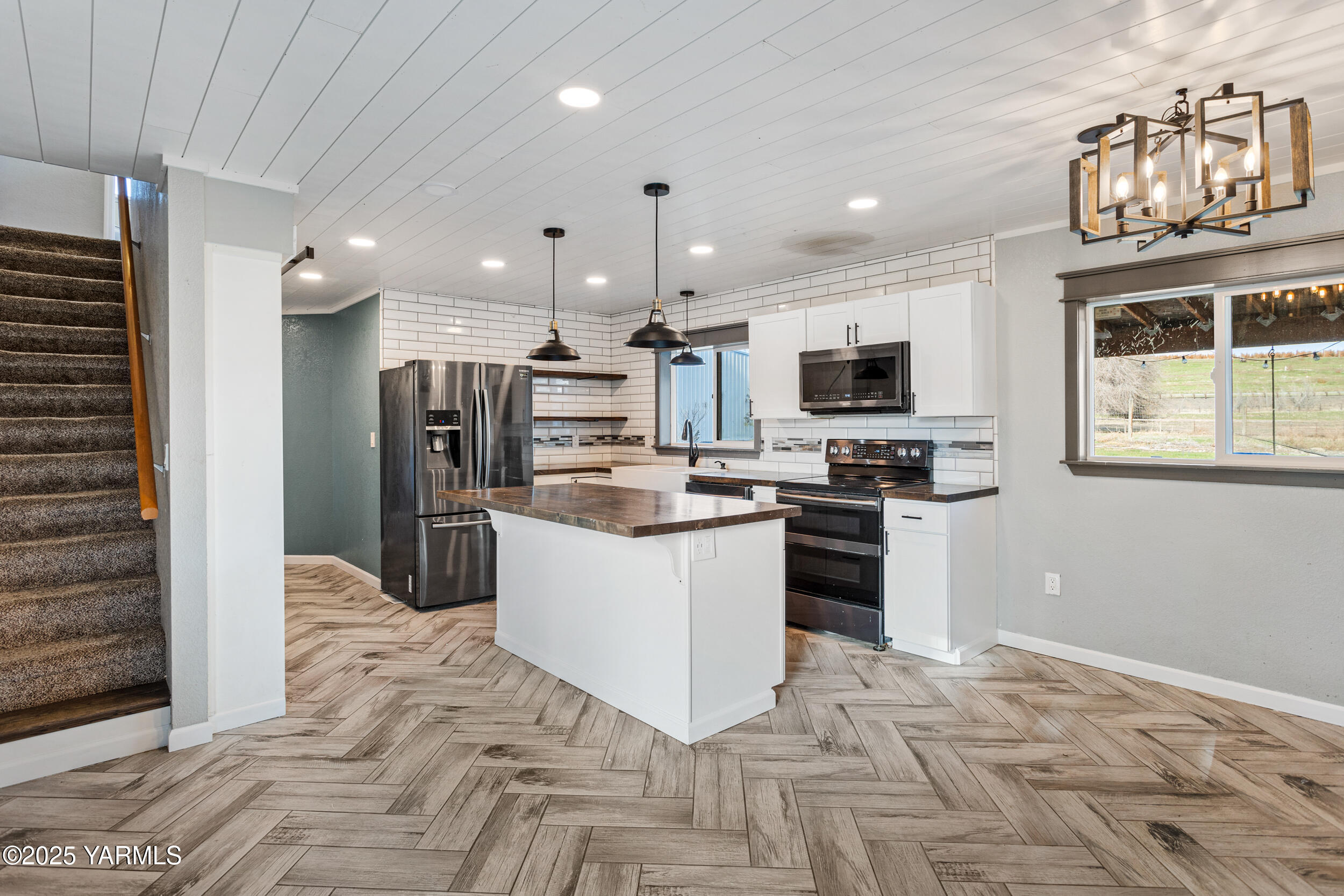 11501 Gilbert Road Yakima, WA 98903 - Photo 24 of 47 a kitchen with stainless steel appliances kitchen island granite countertop a refrigerator oven a sink dishwasher and white cabinets with wooden floor