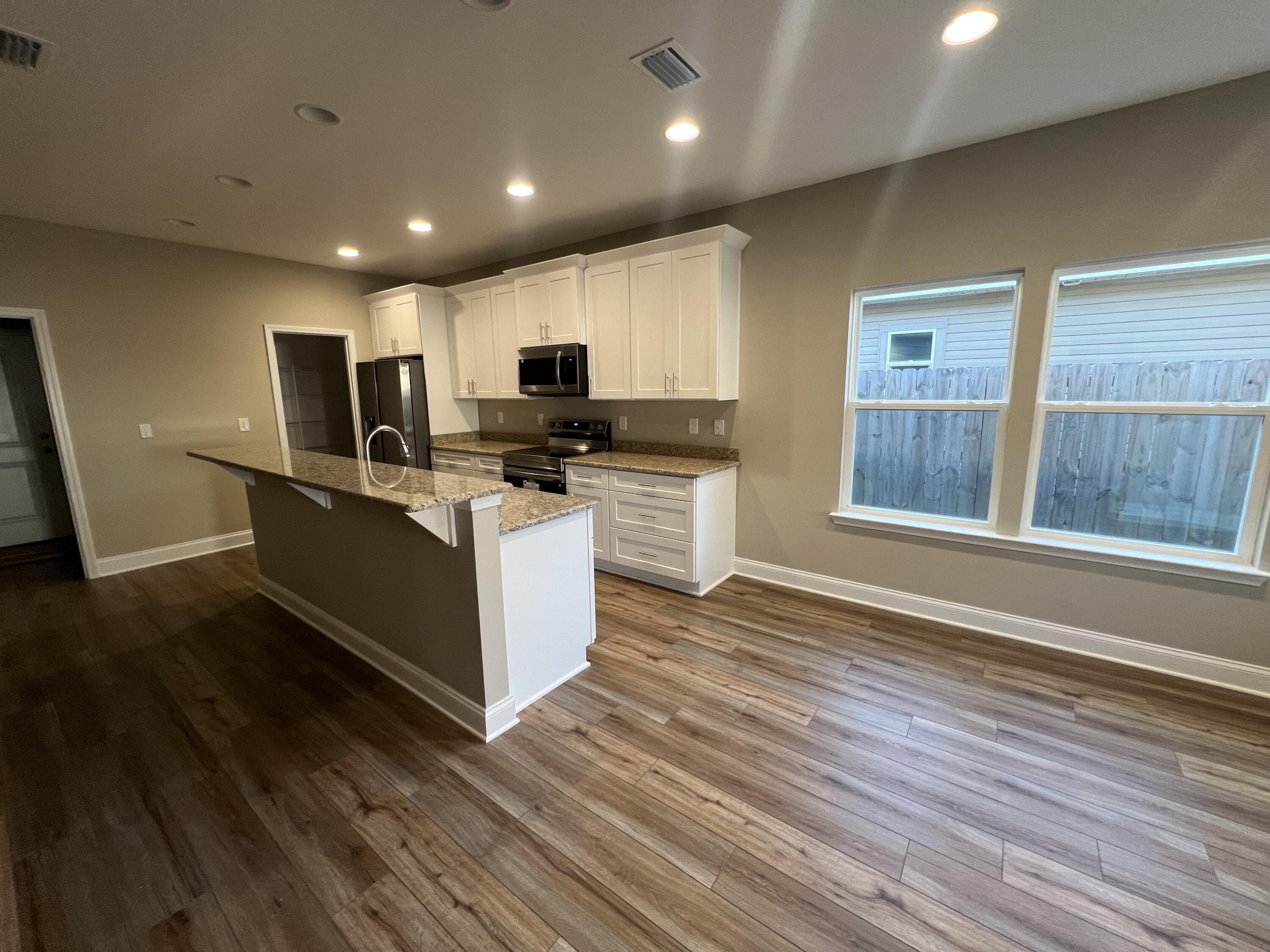 89 Hawkins Road Fort Walton Beach, FL 32547 - Photo 4 of 12 a kitchen with kitchen island microwave stove refrigerator and wooden floor