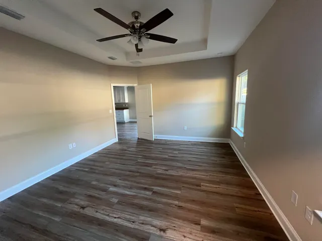 a view of a hallway with wooden floor and a ceiling fan