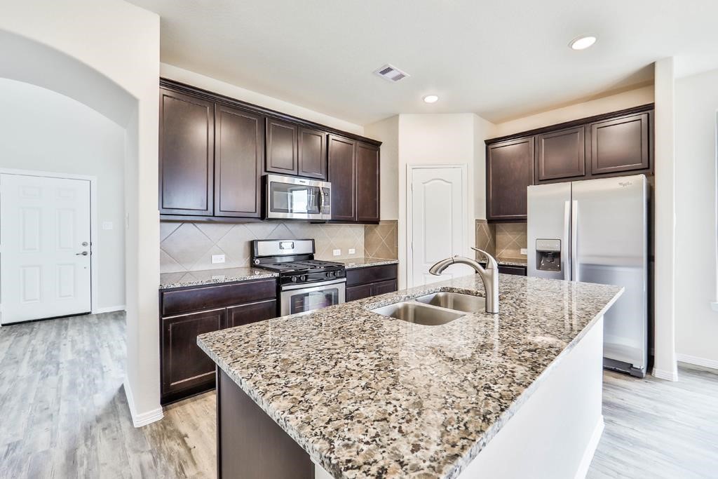 247 Sintra Lk Way Rosenberg, TX 77469 - Photo 8 of 28 a kitchen with kitchen island granite countertop a sink refrigerator and cabinets
