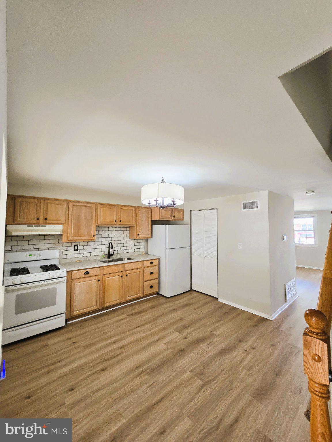 7842 St Bridget Lane Baltimore, MD 21222 - Photo 3 of 13 a kitchen with a wooden floor and white appliances