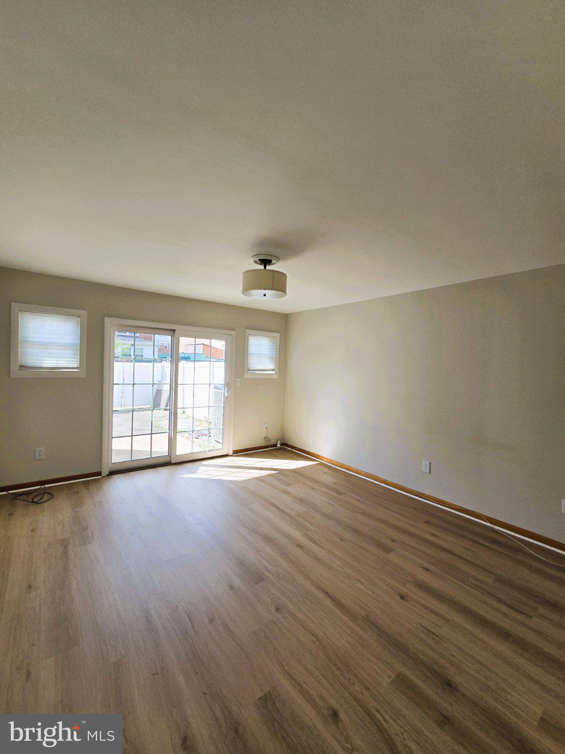 7842 St Bridget Lane Baltimore, MD 21222 - Photo 6 of 13 an empty room with wooden floor and windows