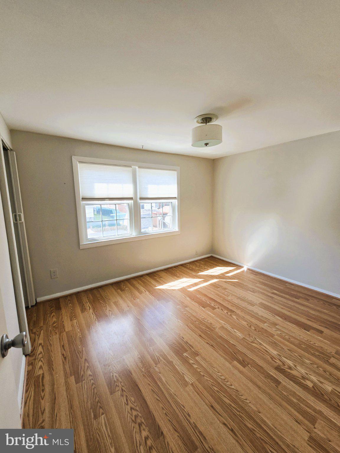 7842 St Bridget Lane Baltimore, MD 21222 - Photo 7 of 13 an empty room with wooden floor and windows
