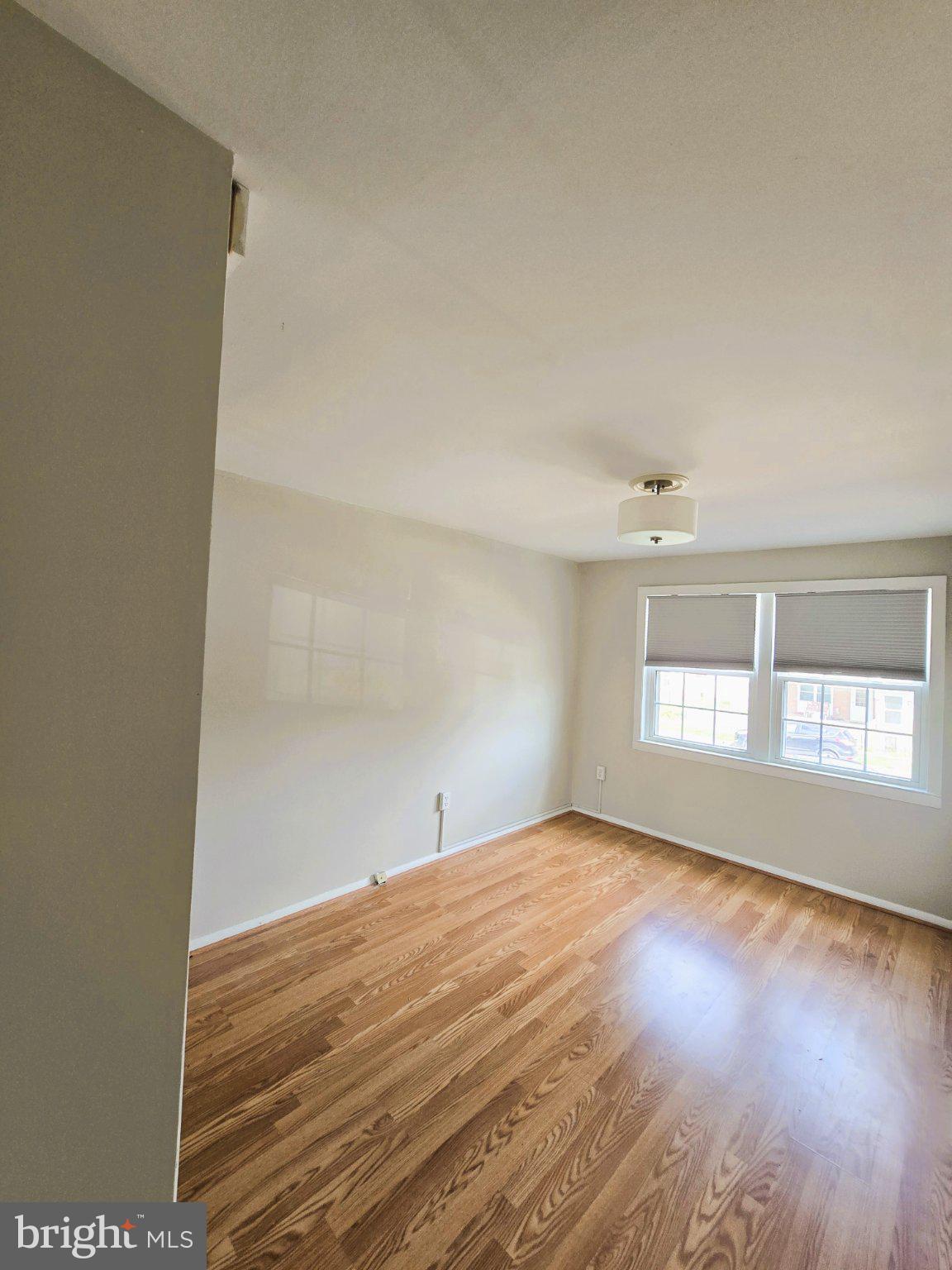 7842 St Bridget Lane Baltimore, MD 21222 - Photo 8 of 13 an empty room with wooden floor and windows