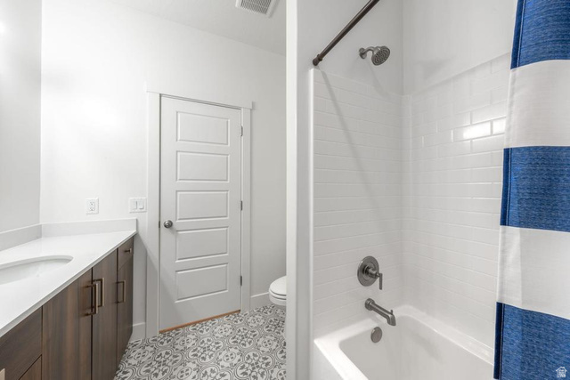 5963 Flattop Drive St. George, UT 84790 - Photo 33 of 45 Bathroom featuring a wood-finish vanity with an integrated white sink, a solid surface countertop, white subway tile shower surround, and patterned floor tiling