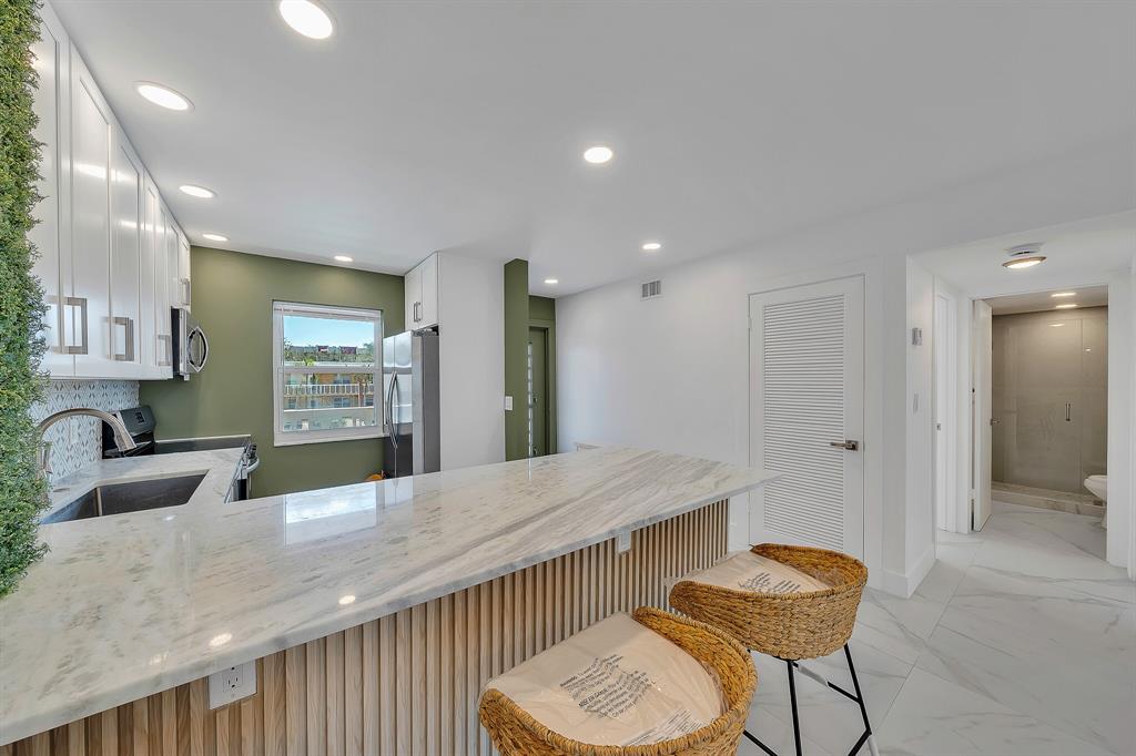 9818 Marina Boulevard, Unit 1225 Boca Raton, FL 33428 - Photo 4 of 17 a kitchen with granite countertop sink and refrigerator
