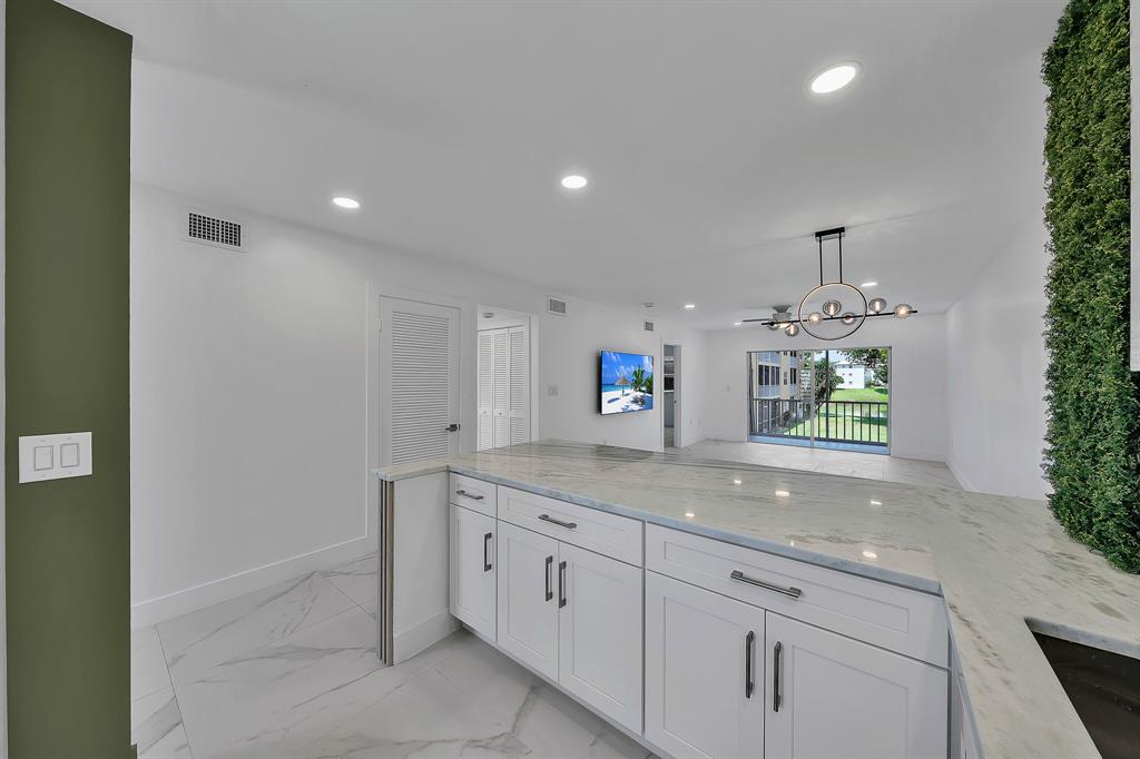 9818 Marina Boulevard, Unit 1225 Boca Raton, FL 33428 - Photo 5 of 17 a hallway with sink and mirror
