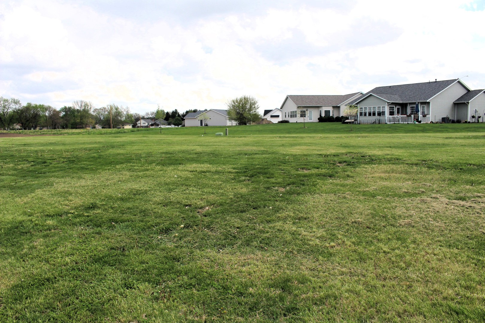 a view of a green field with house in the background