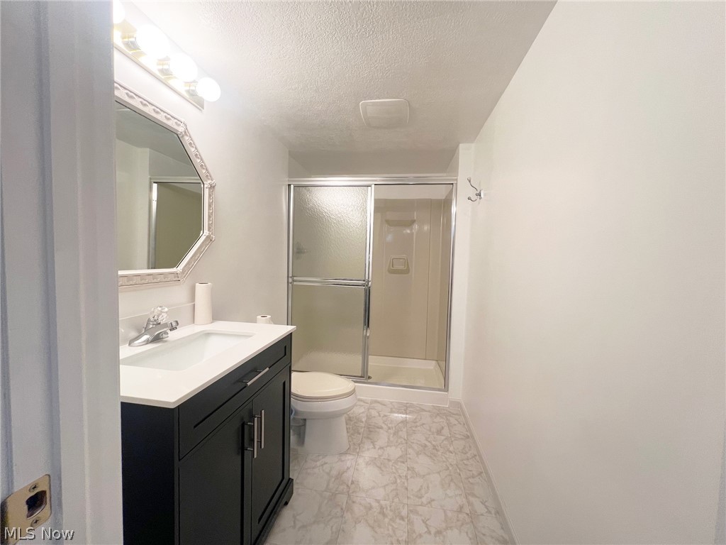 5203 Ridgeland Street Lorain, OH 44055 - Photo 23 of 39 Bathroom featuring vanity, a textured ceiling, a shower with door, toilet, and tile flooring