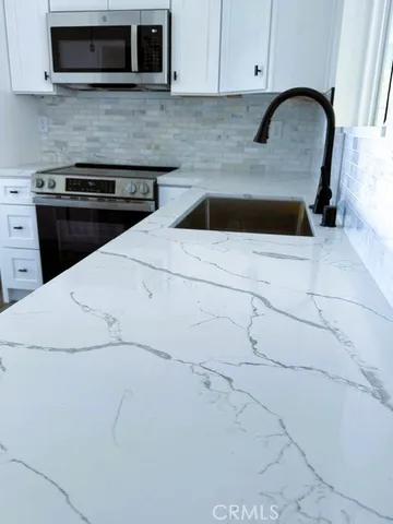 a kitchen with granite countertop white cabinets and stainless steel appliances