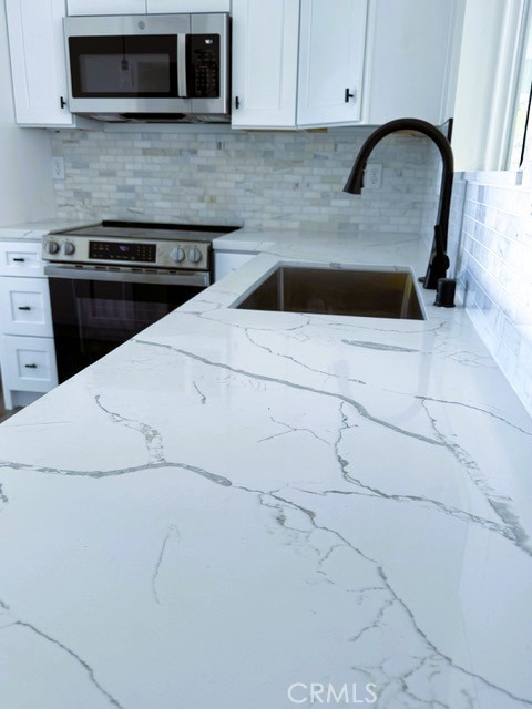 16196 Rancherias Road Apple Valley, CA 92307 - Photo 8 of 19 a kitchen with granite countertop white cabinets and stainless steel appliances