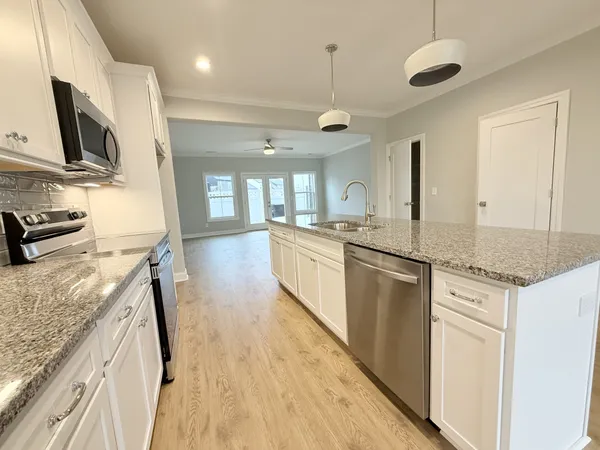 a large kitchen with stainless steel appliances granite countertop a lot of counter space and wooden floor