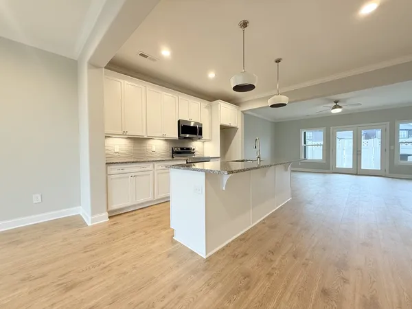 a kitchen with kitchen island granite countertop a sink cabinets and wooden floor