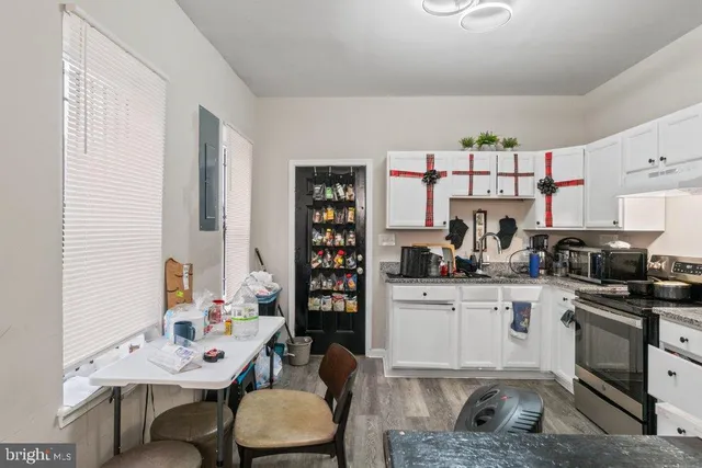 a kitchen with stainless steel appliances a sink a stove a table and chairs