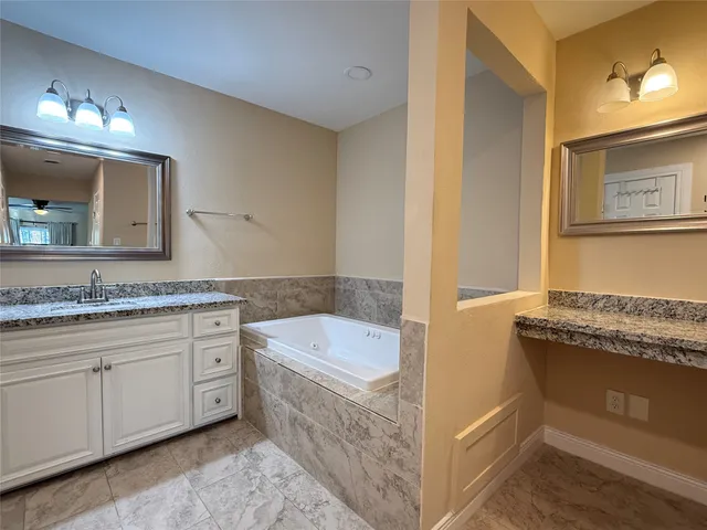 a bathroom with a granite countertop double vanity sink and mirror