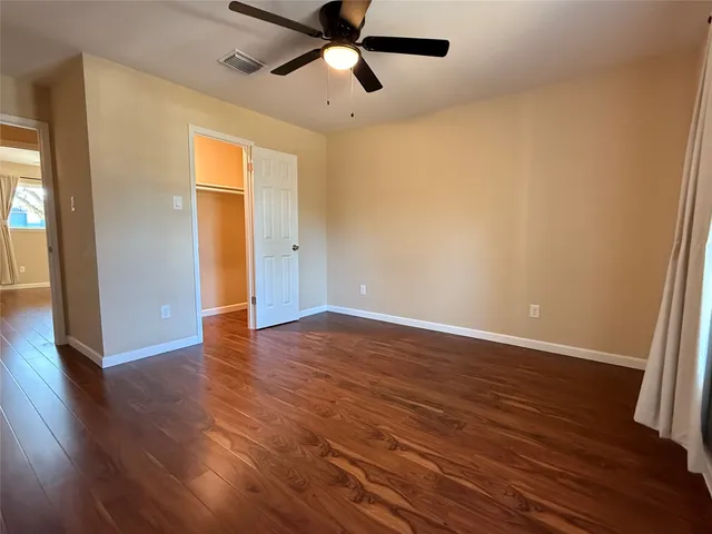 an empty room with wooden floor and a ceiling fan