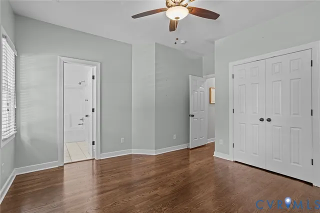 an empty room with wooden floor and ceiling fan