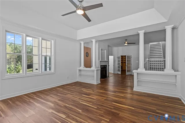 a view of an empty room with wooden floor and a window