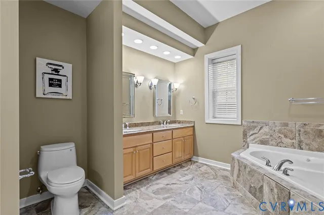 a spacious bathroom with a tub sink toilet and mirror