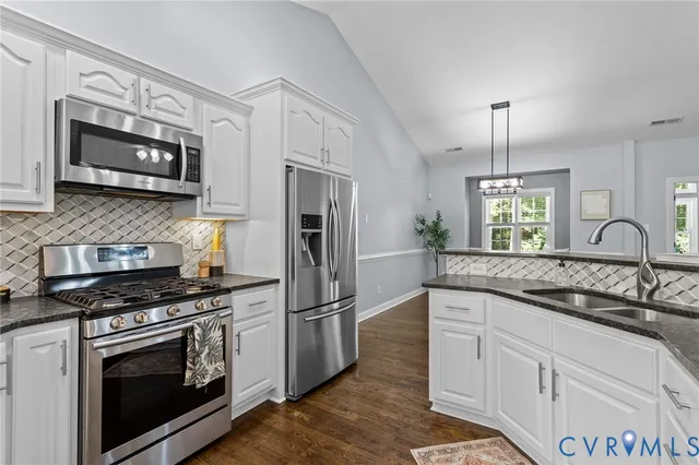a kitchen with granite countertop white cabinets and stainless steel appliances