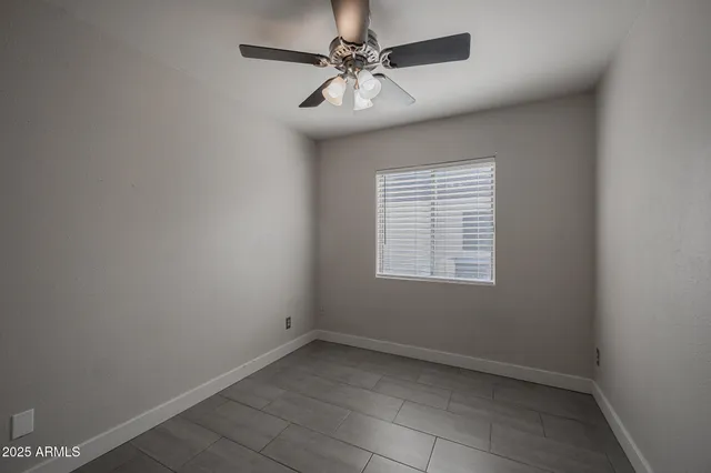 an empty room with a chandelier fan and windows